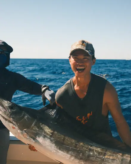 Two reps holding a marlin on a fishing trip